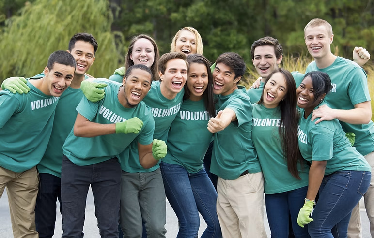 Groupe de bénévoles souriants en t-shirts verts.